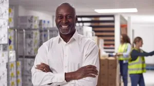 Smiling supply chain manager in warehouse. Logistics team, distribution, and inventory management.