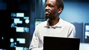 AWS Certified Solutions Architect Associate, man with laptop in server room.