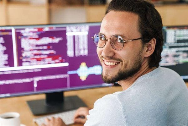 AWS Certified Solutions Architect: Man smiles at computer with code.