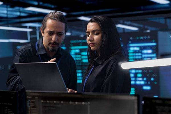 AWS Certified SysOps Administrator Associate: IT professionals using a laptop in a server room.