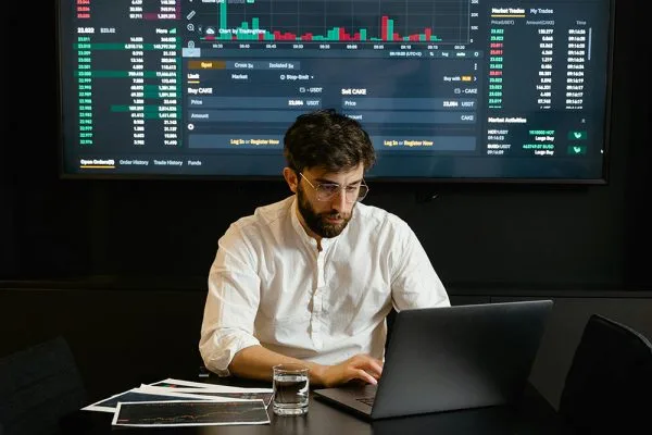 Google Data Engineer: Man analyzes financial data on laptop. Stock market charts displayed. Data analysis and engineering concept.