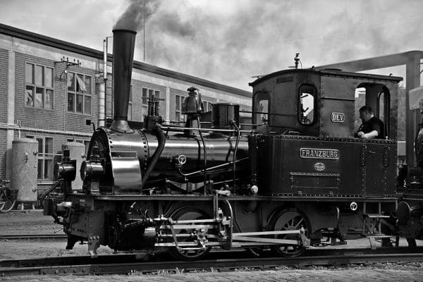 Vintage steam train Franzburg in black and white. History of rail transport. Antique locomotive with driver.