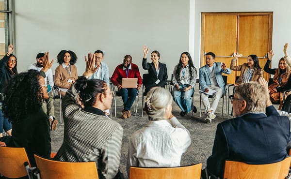 Adult workshop group learning. Diverse people in circle raising hands. Training session.