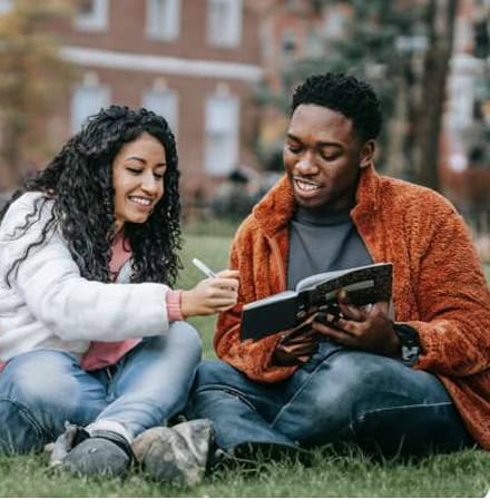 Landing pages: Students studying together outdoors. Woman with pen, man with notebook on campus lawn.